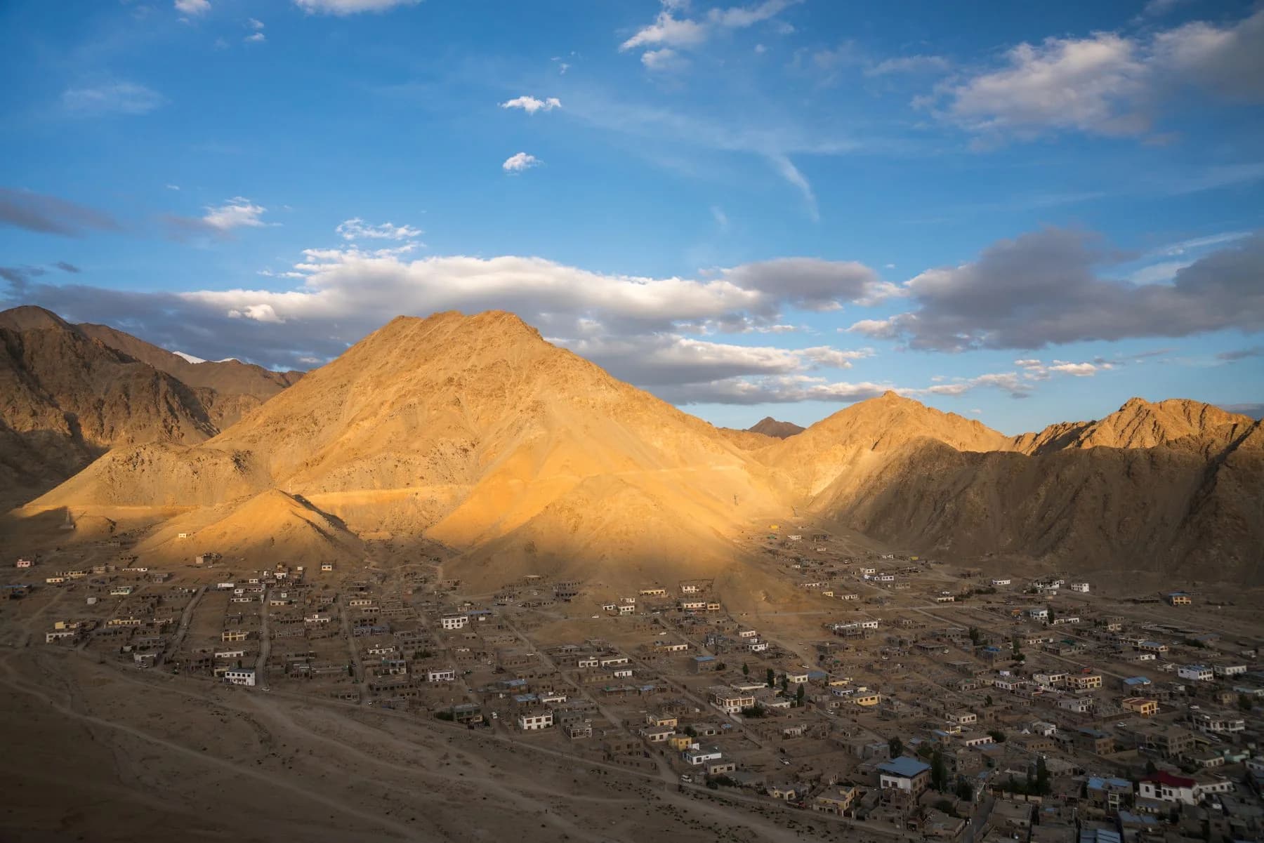 Golden evening light over the mountains and city of Leh